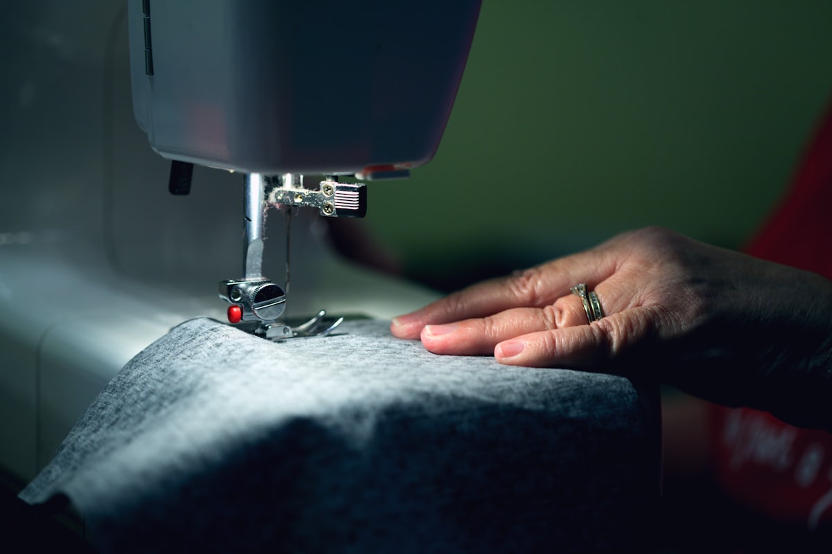 Manos cosiendo una prenda a máquina en el taller